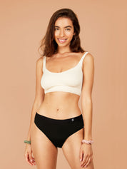 Woman smiling and looking content while wearing black hipster style period pants with waistband