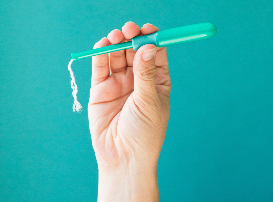 Close-up of a hand holding a tampon applicator, showing the product clearly.